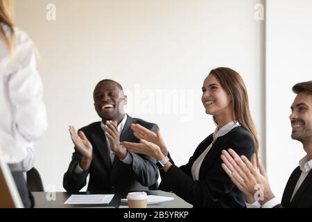 Gemischte Rasse glückliche Mitarbeiter, die dem Sprecher Beifall spenden. Stockfoto