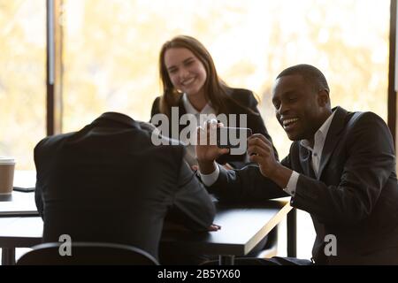 Fröhliche gemischte Rennkollegen, die Spaß an einem eingeschlagenen Teamkollegen haben. Stockfoto