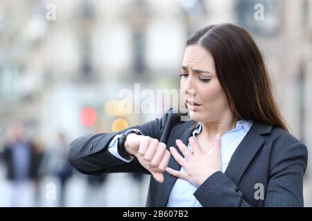 Das Porträt einer besorgten Geschäftsfrau, die die Brustüberprüfung abhielt, erschreckte ihren Puls auf einer intelligenten Uhr auf einer Straße in der Stadt Stockfoto