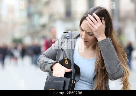 Vorderansicht einer besorgten Frau, die in ihrer Tasche auf einer Straße in der Stadt beschäftigt aussieht Stockfoto