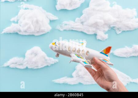 Spielzeugflugzeug in der Hand des Kindes an blauem bewölktem Himmel Stockfoto
