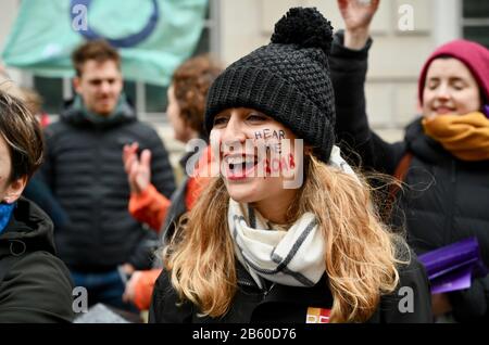 Frau mit Gesicht bemalten Slogan 'Hear Me Roar'. March4Frauen. Internationaler Frauentag für Gleichstellung und Klimagerechtigkeit, Whitehall Place, London. VEREINIGTES KÖNIGREICH Stockfoto