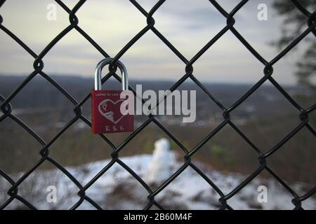 Ein einziges Vorhängeschloss mit einem darin verkratzten Herz mit Initialen und einem Liebeszitat, das an einem Zaun um Flag Rock bei Norton Virgin angebracht ist Stockfoto