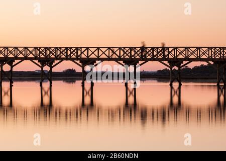 Holzbrücke bei Sonnenuntergang mit Silhouetten von Menschen. Quinta Lago Stockfoto