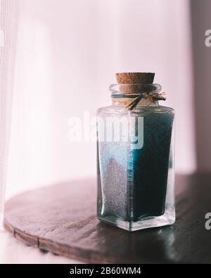 Edle Flasche mit blauen Badesalzen für entspannende Spa-Behandlungen mit weißem Hintergrund und Tageslicht Stockfoto