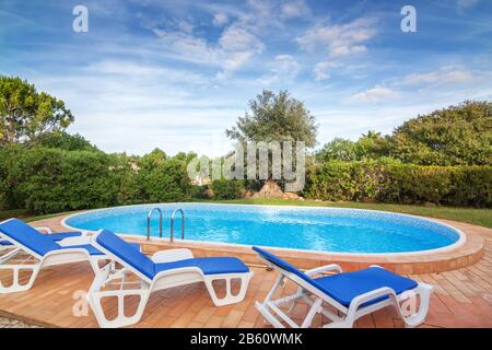 Pool im Garten mit Sonnenliegen zur Entspannung. Mit reinem Wasser. Stockfoto