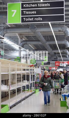 Britische Supermarktregale in der toilettenwalze/dem Papiergang des Ladens leer, während Menschen wegen Coronavirus in Panik einkaufen und Grundausstattung vorrätigen Stockfoto