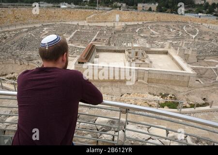 Ein religiöser Jude lehnt sich an ein Geländer, während er ein maßstabsgezeichtes Modell des Tempels des Herodes und Jerusalems in der zweiten Tempelperiode betrachtet, wie es vor seiner Zerstörung durch die Römer 66 n. Chr. war, auf dem Campus des Israel Museums in West-Jerusalem platziert Stockfoto