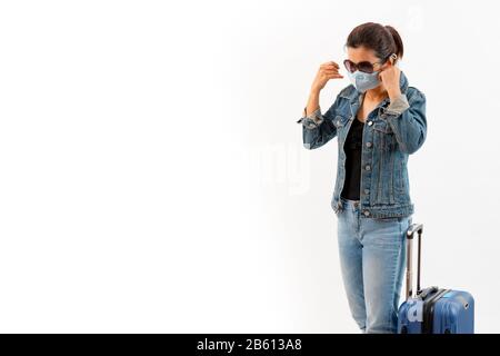 Ein Tourist in der medizinischen Maske steht in der Nähe von Gepäck isoliert auf weißem Hintergrund. Neuartiger COVID-19-Coronavirus-Ausbruch, Mensch verhindert Grippe und Corona-Virus i Stockfoto