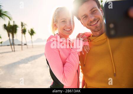 Sportliches Paar macht selfie am Strand Stockfoto