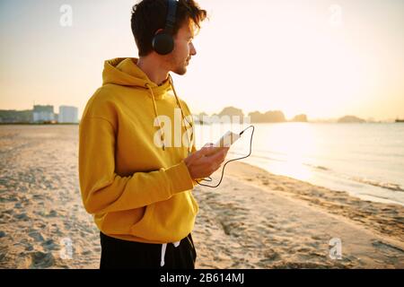 Junger Mann, der Musik am Strand hört Stockfoto