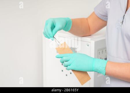 Die Hand reinigt Pinzetten, die in Handtüten eingesetzt werden. Ultraschallreiniger. Stockfoto