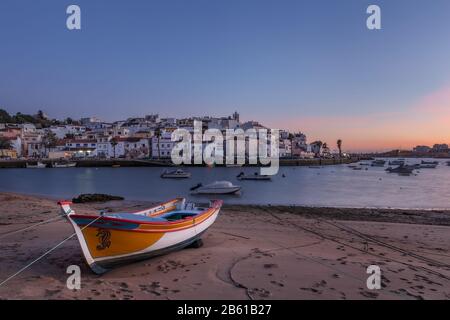 Abend über dem Fischerdorf Ferragudo. Traditionelles Boot im Vordergrund. Stockfoto