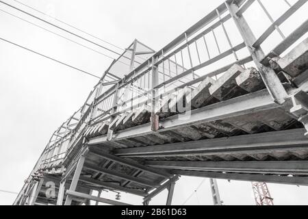 Treppen der Fußgängerbrücke über Bahngleise. Untere Ansicht. Technische Struktur für eine sichere Bewegung von Menschen. Stockfoto