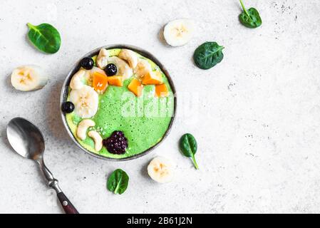 Green Smoothie Bowl für gesundes veganes Detox-Frühstück, Draufsicht, Kopierbereich. Frische Spinatglätte mit Früchten und Nüssen. Gesunde Rohbeschichtungen Stockfoto