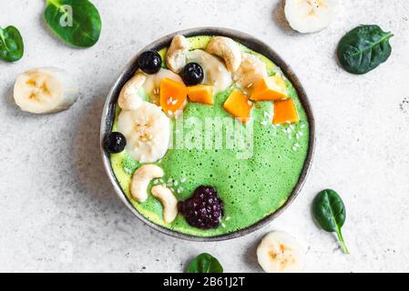 Green Smoothie Bowl für gesundes veganes Detox-Frühstück, Draufsicht, Kopierbereich. Frische Spinatglätte mit Früchten und Nüssen. Stockfoto