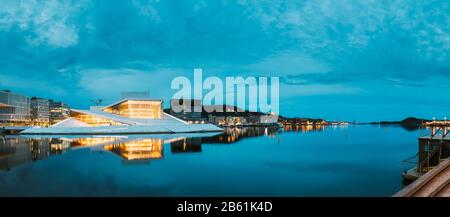 Oslo, Norwegen - 24. Juni 2019: Malerischer Nachtabend Mit Blick Auf Die Beleuchtete Norwegische Nationaloper Und Das Balletthaus Inmitten Des Modernen High-Rise-Gebäudes Stockfoto