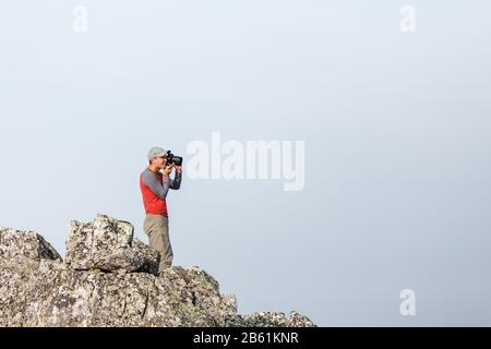 Naturfotograf mit Digitalkamera auf dem Felsen Stockfoto