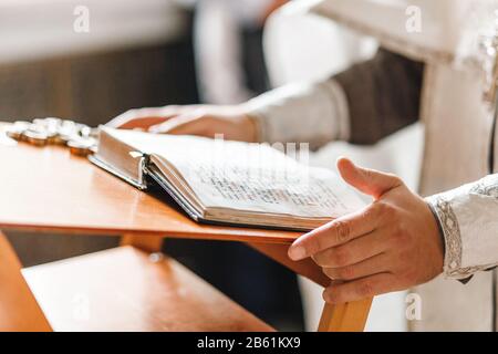 Priester übergibt sich beim Gottesdienst das geöffnete bibelbuch Stockfoto