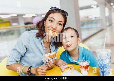 Mutter und Sohn essen gebratene Kartoffeln und haben zusammen Spaß im Haus. Stockfoto