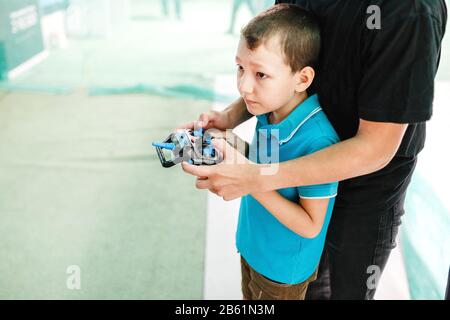 Liebenswürdiger Junge, der mit drahtloser Fernbedienung mit Quadrocopter-Spielzeug zusammen mit seinem Vater spielt Stockfoto