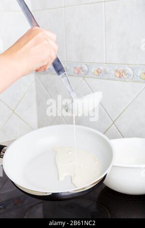 Mädchen in einer Pfanne braten die Pfannkuchen. Zuhause in der Küche. Nahaufnahme. Stockfoto