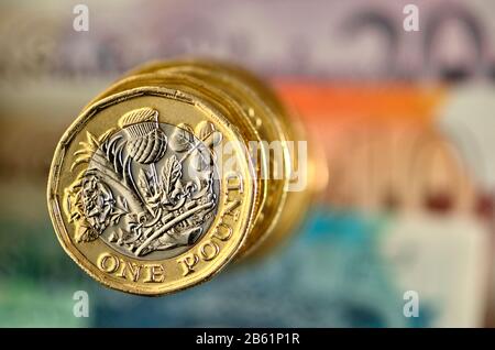 Stapel britischer Pfund-Münzen auf Banknoten Stockfoto