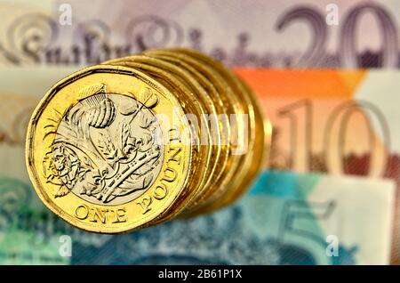 Stapel britischer Pfund-Münzen auf Banknoten Stockfoto