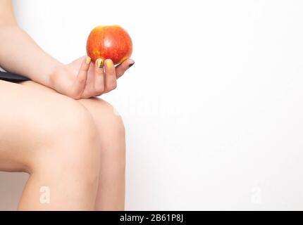 Mädchen hält einen apfel auf dem Hintergrund der Knie. Gesundes Esskonzept für Gelenke. Gemeinsame Gesundheitskost Stockfoto