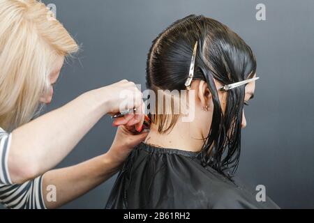 Friseursalon schneidet braune Haare mit einer Schere Stockfoto