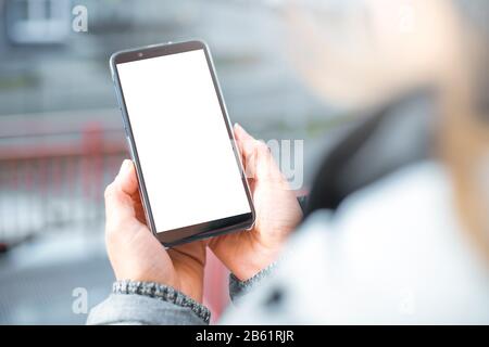 Smartphone mit weißem Bildschirm in der Hand. Frau hält ein Handy. Stockfoto