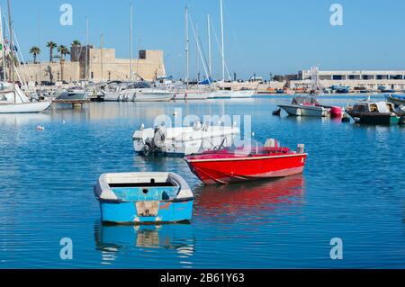 Bari, ITALIEN - 16. FEBRUAR 2020: Rustikale Boote im Fischerhafen vor dem Hintergrund moderner Jachten und des Castello Svevo in Bari, Apulien Stockfoto