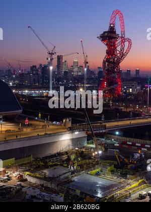 London, England, Großbritannien - 4. Dezember 2019: Hinter dem ArcelorMittal Orbit Tower und Wolkenkratzern des Docklands Finanzdistrikts in East Lon geht die Sonne unter Stockfoto
