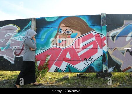 Makassar, Süd-Sulawesi, Indonesien. März 2020. Eine Frau, die einen Hijab trägt, spaziert vor einer Wand voller Wandbilder rund um Losari Beach, Makassar City, South Sulawesi Provinz, Indonesien. Gutschrift: Herwin Bahar/ZUMA Wire/Alamy Live News Stockfoto