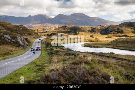 Lochinver, Schottland, Großbritannien - 19. September 2017: Motorradfahrer fahren auf der A837 Road, Teil der North Coast 500 Route, neben Flüssen und niedrigen Hügeln in t Stockfoto