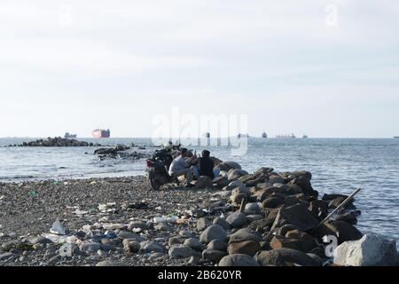 Makassar, Süd-Sulawesi, Indonesien. März 2020. Zwei Männer sitzen am Nachmittag am Strand und genießen den Blick auf den Strand rund um Makassar City, Provinz Sulawesi, Indonesien. Gutschrift: Herwin Bahar/ZUMA Wire/Alamy Live News Stockfoto