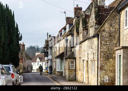 Tisbury, England, Großbritannien - 18. Februar 2017: Fußgänger gehen an traditionellen Steinhäusern im Wiltshire Dorf Tisbury vorbei. Stockfoto