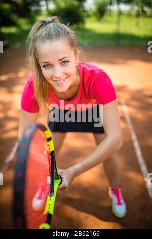 Hübsche, junge Frau Tennisspielerin, die auf einem Tonplatz spielt. Gesundes aktives Lifestyle-Konzept Stockfoto