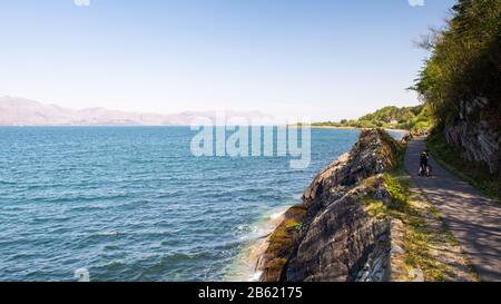 Appin, Schottland, Großbritannien - Mai 12, 2016: ein Radfahrer fährt entlang des National Cycle Network Caledonia Weg auf einem umgebauten Rail Trail entlang der Küste von Appi Stockfoto