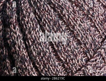 Das Detail eines gerippten, strukturierten, aus reiner britischer Wolle gestrickten Hutes in tweedy-farben von Purpeln und Pinks. Stockfoto