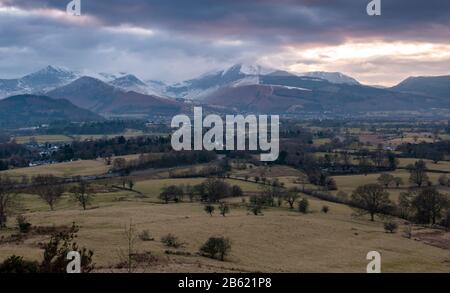 Die schneebedeckten Berge von Derwent Fells ragen hinter Keswick und dem Derwent Valley auf, von Latrigg Hill im Lake District in England aus betrachtet. Stockfoto