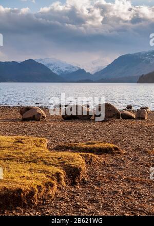 Scheint die Sonne auf den Felsen am Ufer des Derwent Water, mit den Backen der Borrowdale Berge hinter, in der England Lake District. Stockfoto