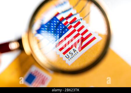 Briefumschlag aus den Vereinigten Staaten mit einem Stempel mit dem Bild der amerikanischen Flagge unter einer Lupe auf weißem Hintergrund Stockfoto