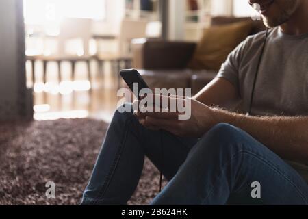 Kaukasischer Mann, der Kopfhörer trägt und sein Telefon verwendet Stockfoto