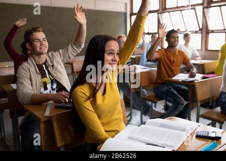 Seitenansicht der Schüler, die ihre Hände in der Klasse heben Stockfoto