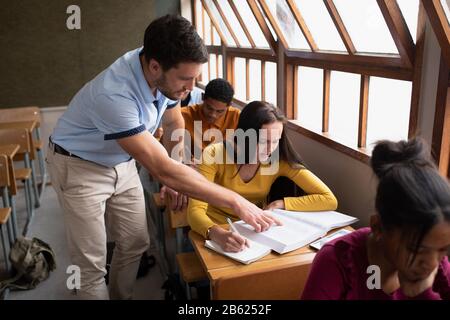 Seitenansicht des Lehrers, der Schülern im Unterricht hilft Stockfoto