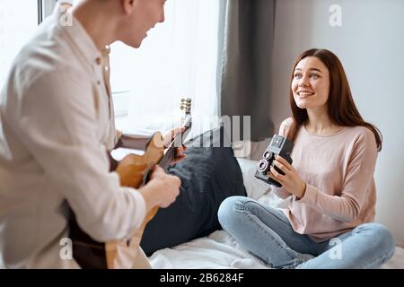 Lernkonzept für soziale Medien, Entspannung und Gitarrenspiel, Junge Frau, die die Glückwünsche ihres Mannes aufzeichnet, Unusula zum Geburtstag, Überraschung. Stockfoto