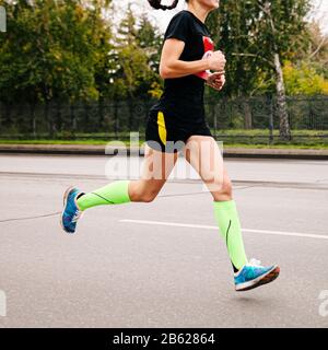 Athletin in Kompressionstrümpfe, die im Straßenmarathon laufen Stockfoto