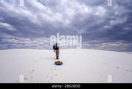 Im White Sand National Park planten mein Mann und ich einen Campingplatz in der Wildnis. Er schleppt unsere Ausrüstung auf den Ort. Stürmisches Wetter aus der Ferne. Stockfoto