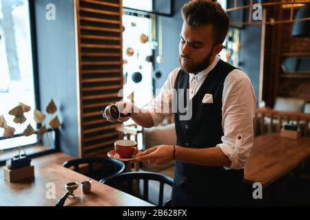 Der fleißige Mann in elegantem Anzug konzentrierte sich auf das verschütten des geerdeten Kaffees, Nahaufnahme der Seitenansicht. Talentkonzept, Menschen Stockfoto